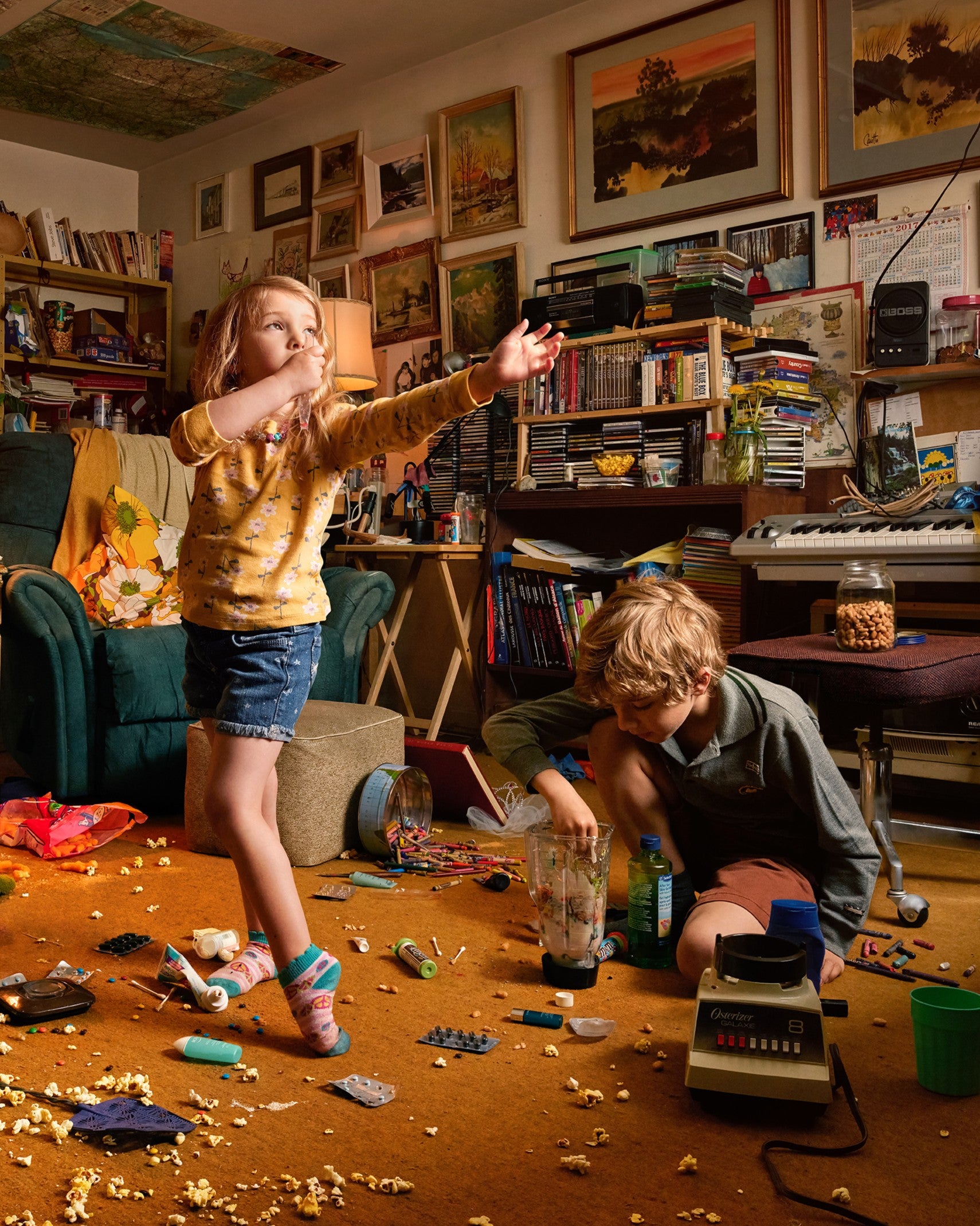 Children playing in a cluttered room with toys and books.